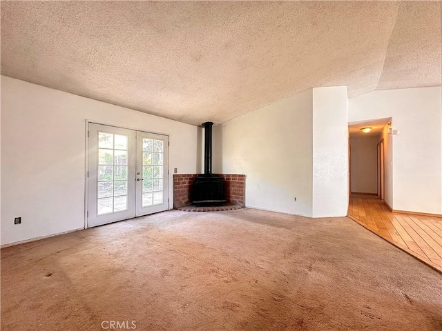 unfurnished living room with french doors, carpet, a textured ceiling, and vaulted ceiling