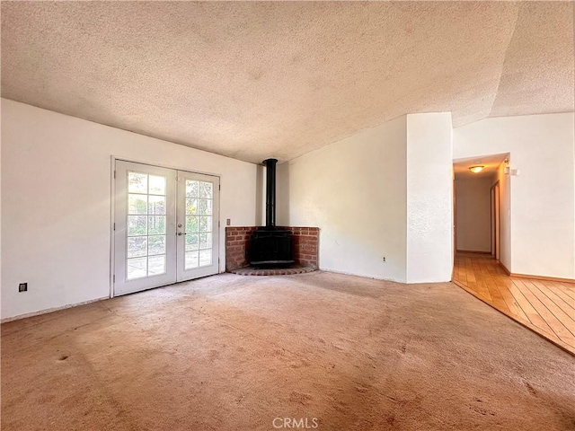 14585 Long View Dr, Fontana, CA 92337 - unfurnished living room with french doors, a textured ceiling, carpet flooring, lofted ceiling, and a wood stove