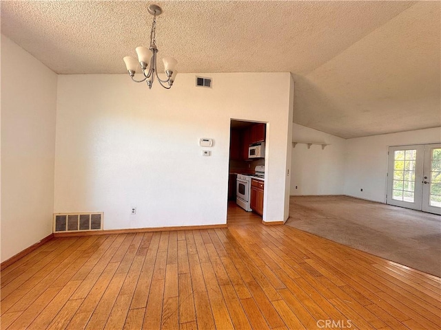 unfurnished room with visible vents, a textured ceiling, a chandelier, and light wood-type flooring