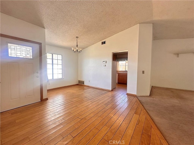 unfurnished dining area with a textured ceiling, an inviting chandelier, a healthy amount of sunlight, and visible vents