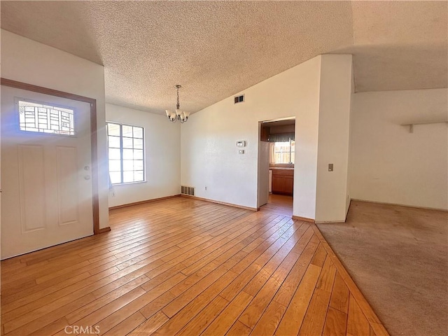 14585 Long View Dr, Fontana, CA 92337 - foyer featuring a chandelier, a textured ceiling, plenty of natural light, light wood-style floors, and vaulted ceiling