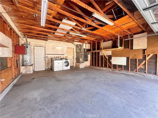 garage featuring water heater, heating unit, and washer and dryer
