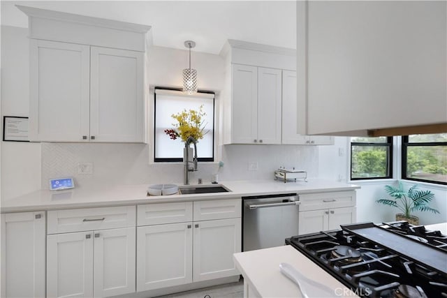kitchen with light countertops, decorative backsplash, stainless steel dishwasher, and a sink