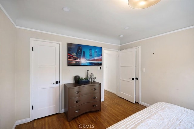bedroom with crown molding, baseboards, and wood finished floors