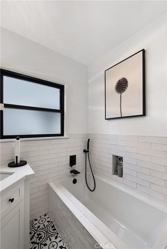full bath with tile patterned floors, a garden tub, and vanity