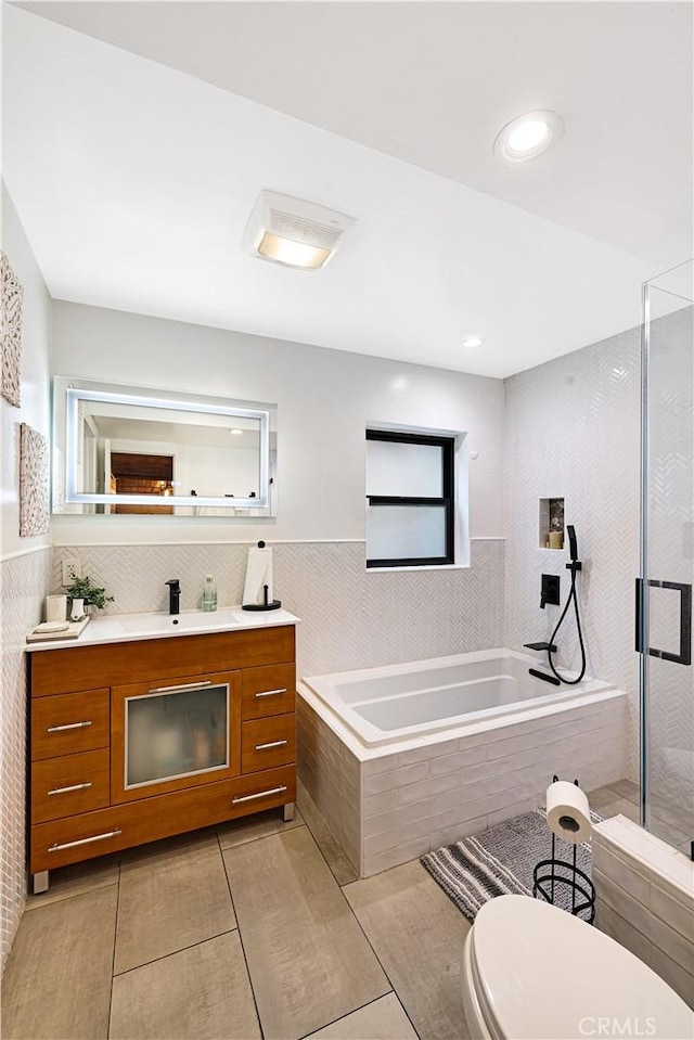 full bathroom featuring vanity, toilet, tile walls, a shower stall, and a garden tub