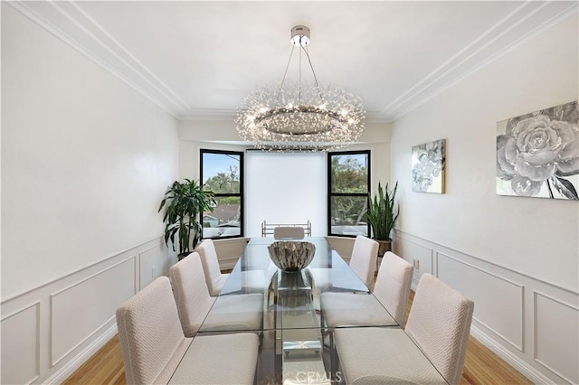 dining room with crown molding, light wood finished floors, a decorative wall, and a notable chandelier