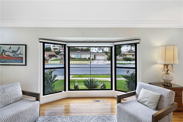 living area featuring crown molding, wood finished floors, and visible vents