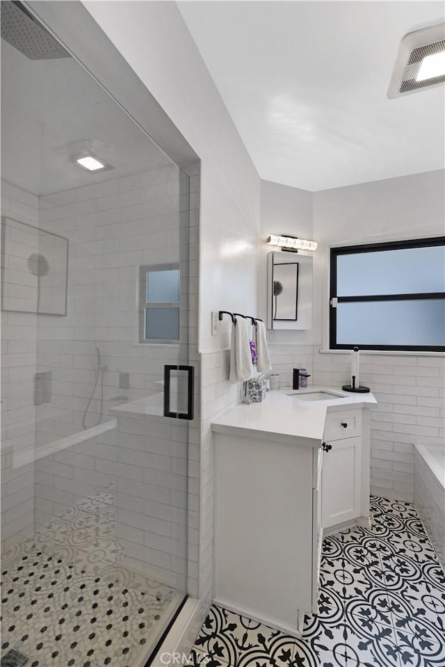 full bath with vanity, tile patterned floors, tile walls, visible vents, and a stall shower