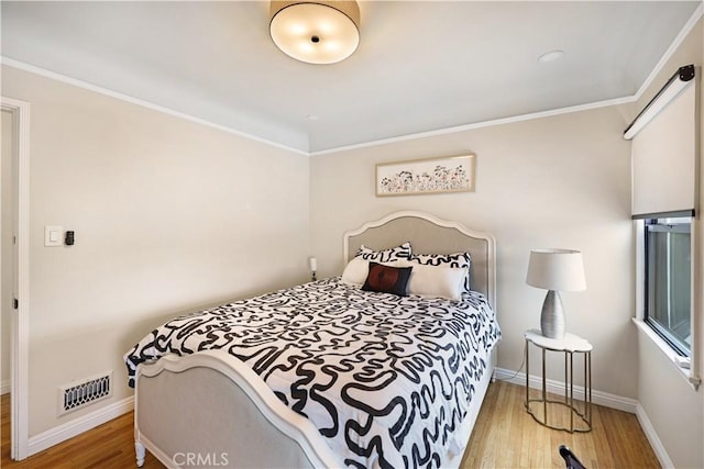 bedroom with crown molding, baseboards, wood finished floors, and visible vents
