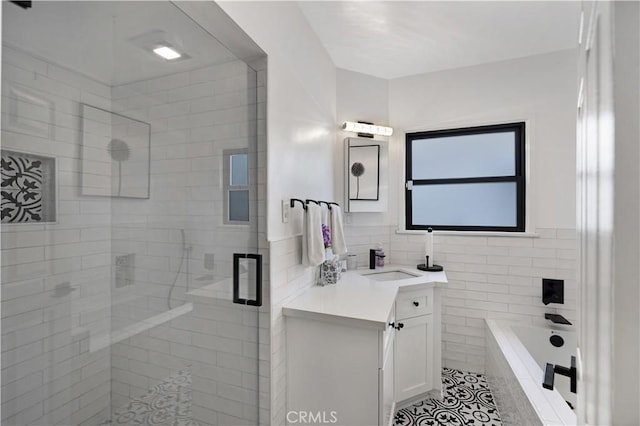 bathroom with tile patterned flooring, vanity, tile walls, a bath, and a stall shower