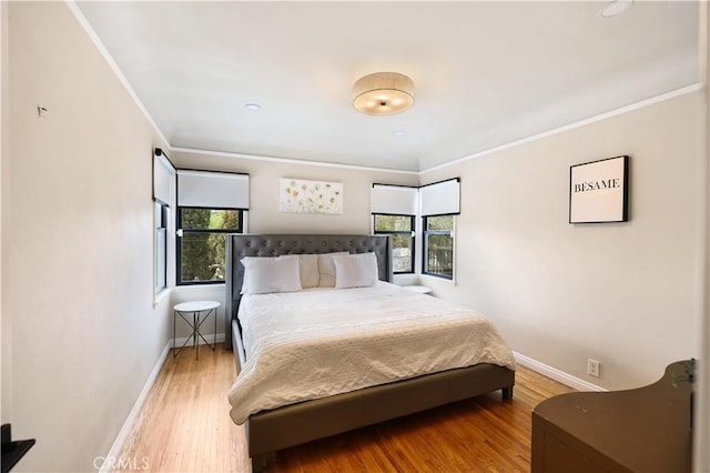 bedroom with baseboards, ornamental molding, and light wood-type flooring