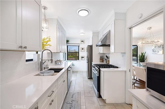 kitchen featuring light countertops, wall chimney exhaust hood, tasteful backsplash, a sink, and stainless steel appliances