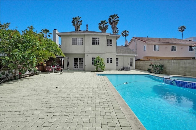 view of swimming pool with a patio, a pool with connected hot tub, central AC unit, and a fenced backyard