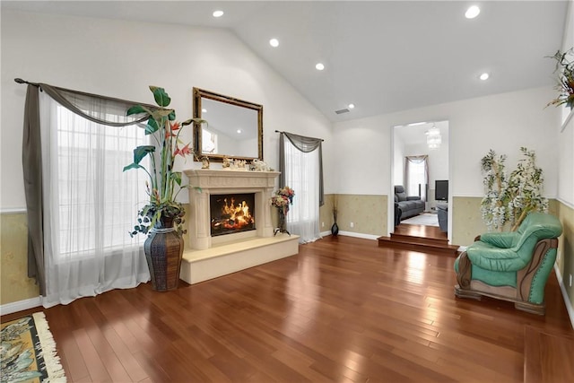living area with wood finished floors, recessed lighting, lofted ceiling, and a lit fireplace