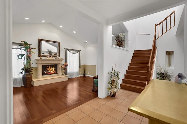 interior space featuring stairs, recessed lighting, wood finished floors, vaulted ceiling, and a lit fireplace
