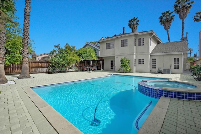 view of swimming pool with a patio, a pool with connected hot tub, and a fenced backyard