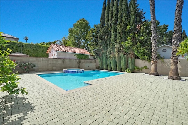view of pool with a fenced backyard, a pool with connected hot tub, and a patio area