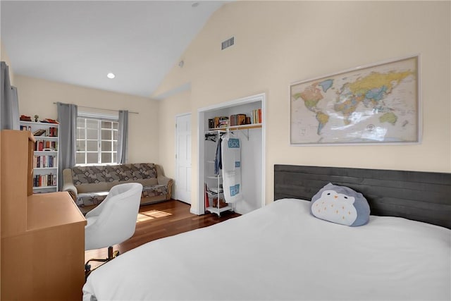 bedroom featuring high vaulted ceiling, a closet, wood finished floors, and visible vents