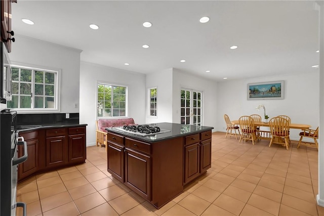 kitchen with dark countertops, a center island, light tile patterned floors, recessed lighting, and white gas stovetop