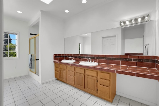 bathroom with double vanity, a shower stall, and a sink