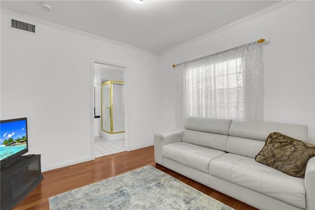 living room featuring baseboards, ornamental molding, wood finished floors, and visible vents