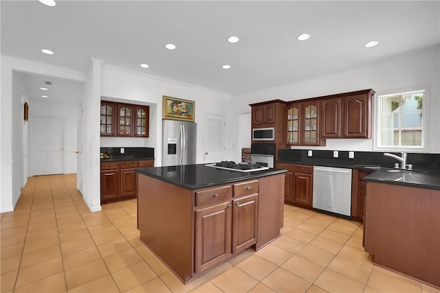 kitchen featuring light tile patterned flooring, a kitchen island, dark countertops, a sink, and stainless steel appliances