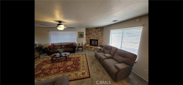 living room with a ceiling fan, a textured ceiling, visible vents, a fireplace, and carpet floors