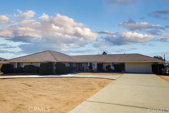 single story home with a garage, driveway, and a chimney