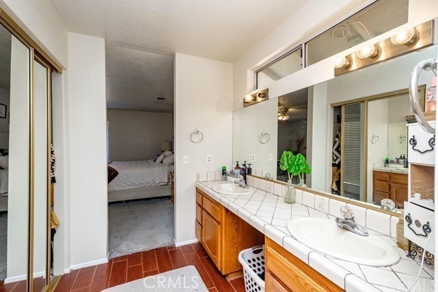 bathroom featuring connected bathroom, ceiling fan, a sink, double vanity, and wood tiled floor
