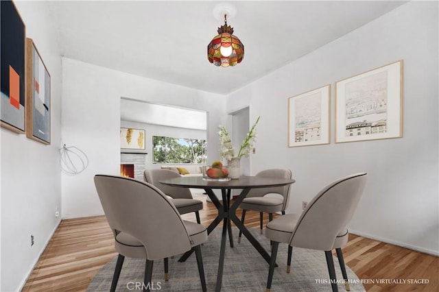 305 Raymondale Dr Unit L, South Pasadena, CA 91030 - dining area with light wood-type flooring, a lit fireplace, and baseboards