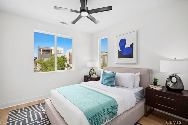 bedroom featuring baseboards, a ceiling fan, wood finished floors, and visible vents