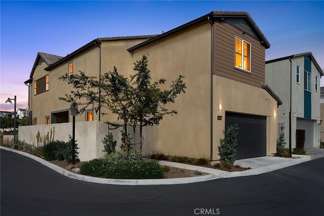 view of front of property featuring fence, an attached garage, driveway, and stucco siding
