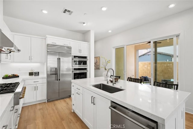 kitchen with visible vents, light wood-style floors, white cabinetry, a sink, and stainless steel appliances