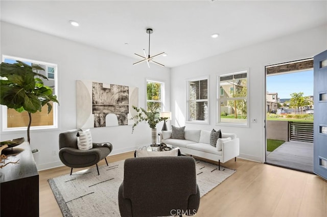 living area featuring light wood-style floors, baseboards, recessed lighting, and a chandelier