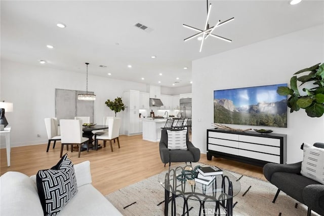 living room with visible vents, recessed lighting, light wood-style flooring, and an inviting chandelier
