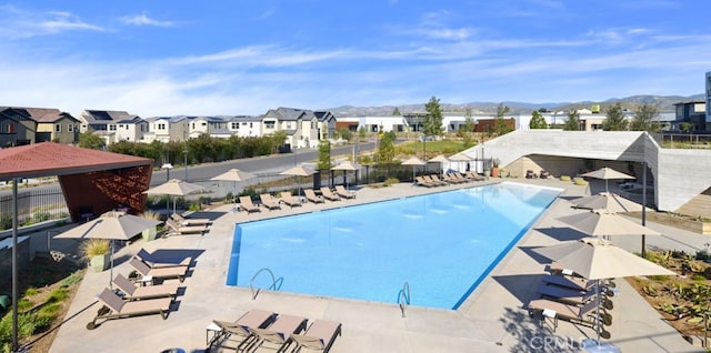 pool featuring a patio, a mountain view, fence, and a residential view