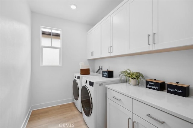 washroom featuring baseboards, cabinet space, washer and dryer, and light wood-style floors