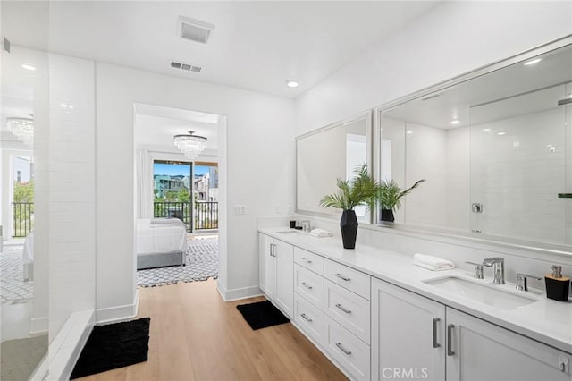 ensuite bathroom featuring double vanity, visible vents, wood finished floors, a sink, and ensuite bathroom