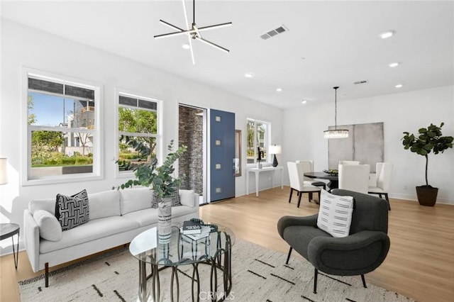 living area featuring a healthy amount of sunlight, light wood-style floors, recessed lighting, and a chandelier