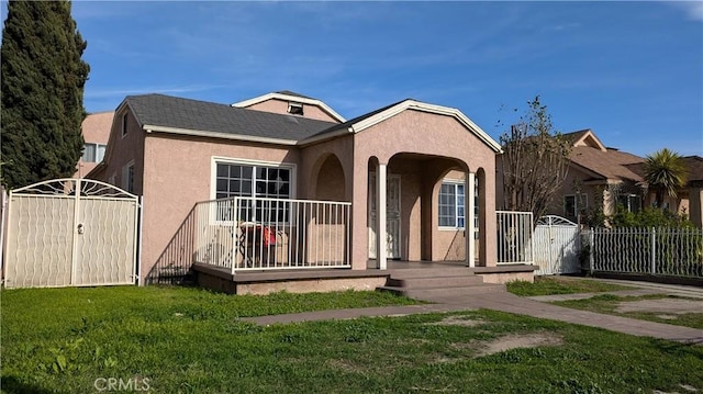 view of front of house with a gate, stucco siding, a front yard, and fence