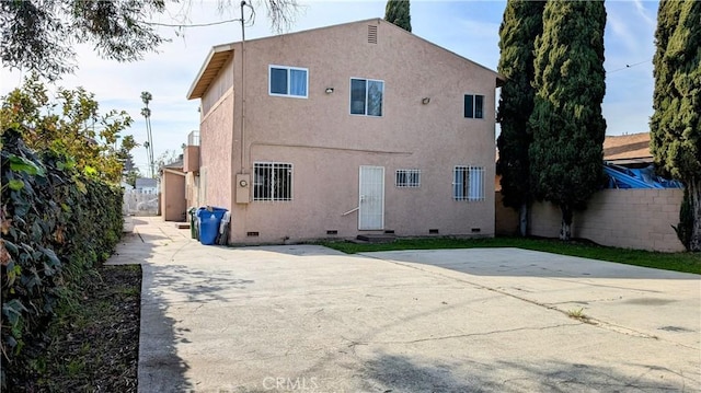 back of house with crawl space, fence, and stucco siding