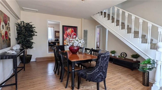 dining area featuring stairs, baseboards, and light wood-style floors