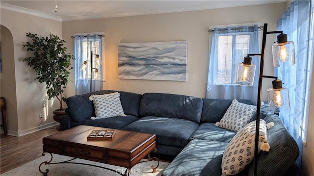 living area with arched walkways, baseboards, ornamental molding, and wood finished floors