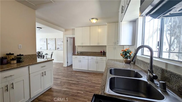 kitchen with a sink, dark stone countertops, white cabinets, and dark wood-style floors