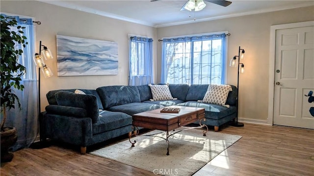 living area with crown molding, baseboards, a ceiling fan, and wood finished floors