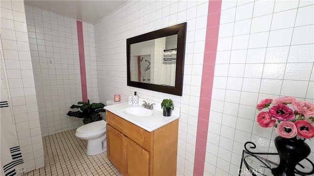 bathroom featuring vanity, toilet, tile patterned floors, a shower with shower curtain, and tile walls
