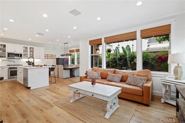 living area featuring recessed lighting, visible vents, and ornamental molding