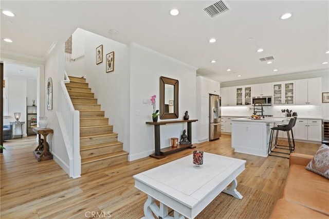 living room with recessed lighting, visible vents, ornamental molding, and stairway