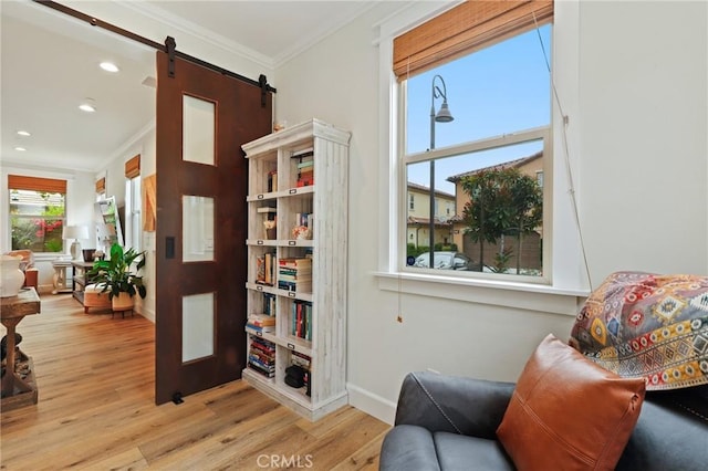 sitting room featuring a barn door, wood finished floors, baseboards, ornamental molding, and recessed lighting
